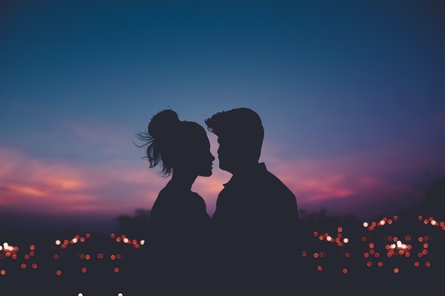 Muž a žena sa bozkávajú pri západe slnka 